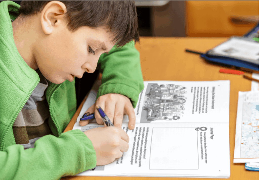 A young boy writing answers to workbook questions in his Watershed Science workbook.